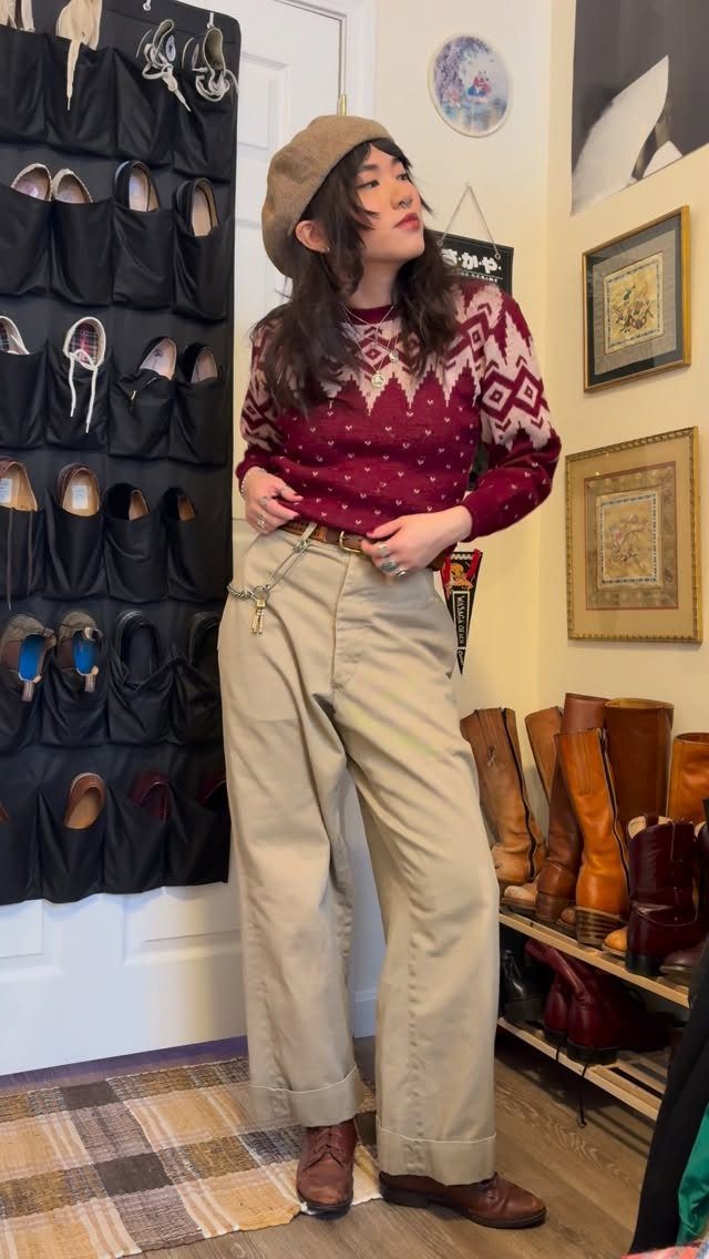 Woman wearing a maroon patterned sweater, khaki trousers, and a brown beret standing near a shoe organizer.