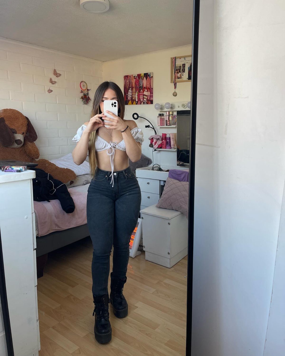 A woman posing in a white cropped top and high-waisted dark jeans.