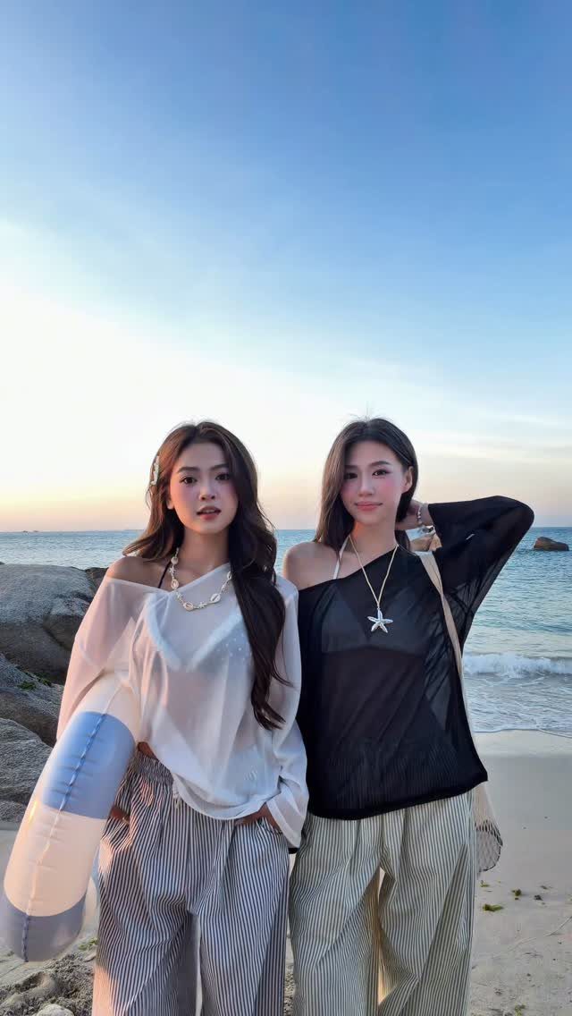 Two women posing on a sandy beach during sunset wearing stylish summer outfits.