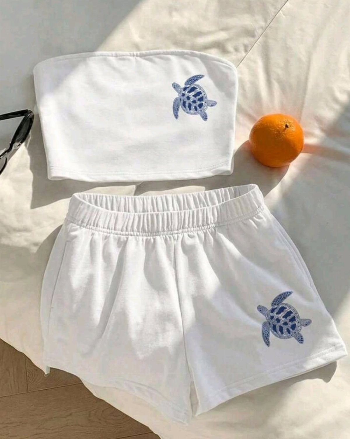 White strapless tube top and shorts set with blue turtle embroidery on white fabric.
