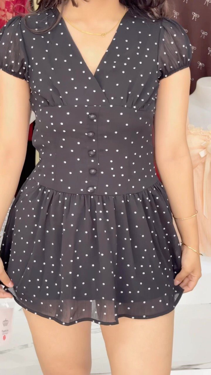 A person wearing a black and white polka dot minidress with short puff sleeves.