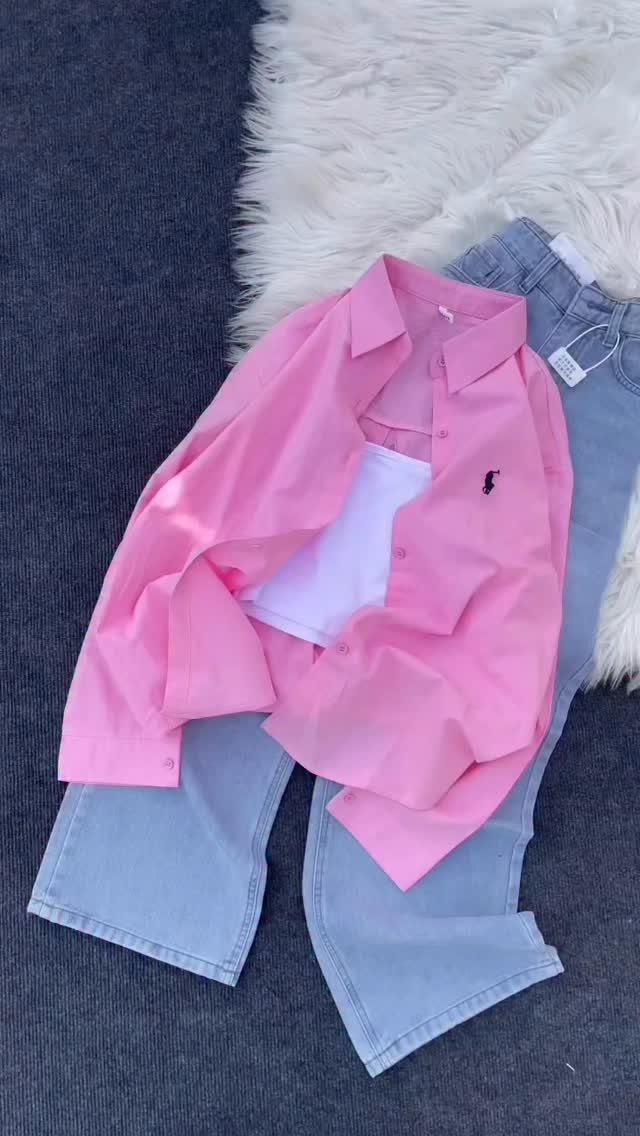 Pink button-down shirt and white top layered over light blue denim pants on white fur.