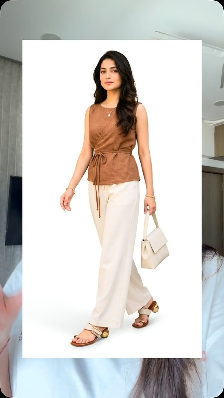 Woman in a brown top and cream trousers wearing brown strappy sandals.
