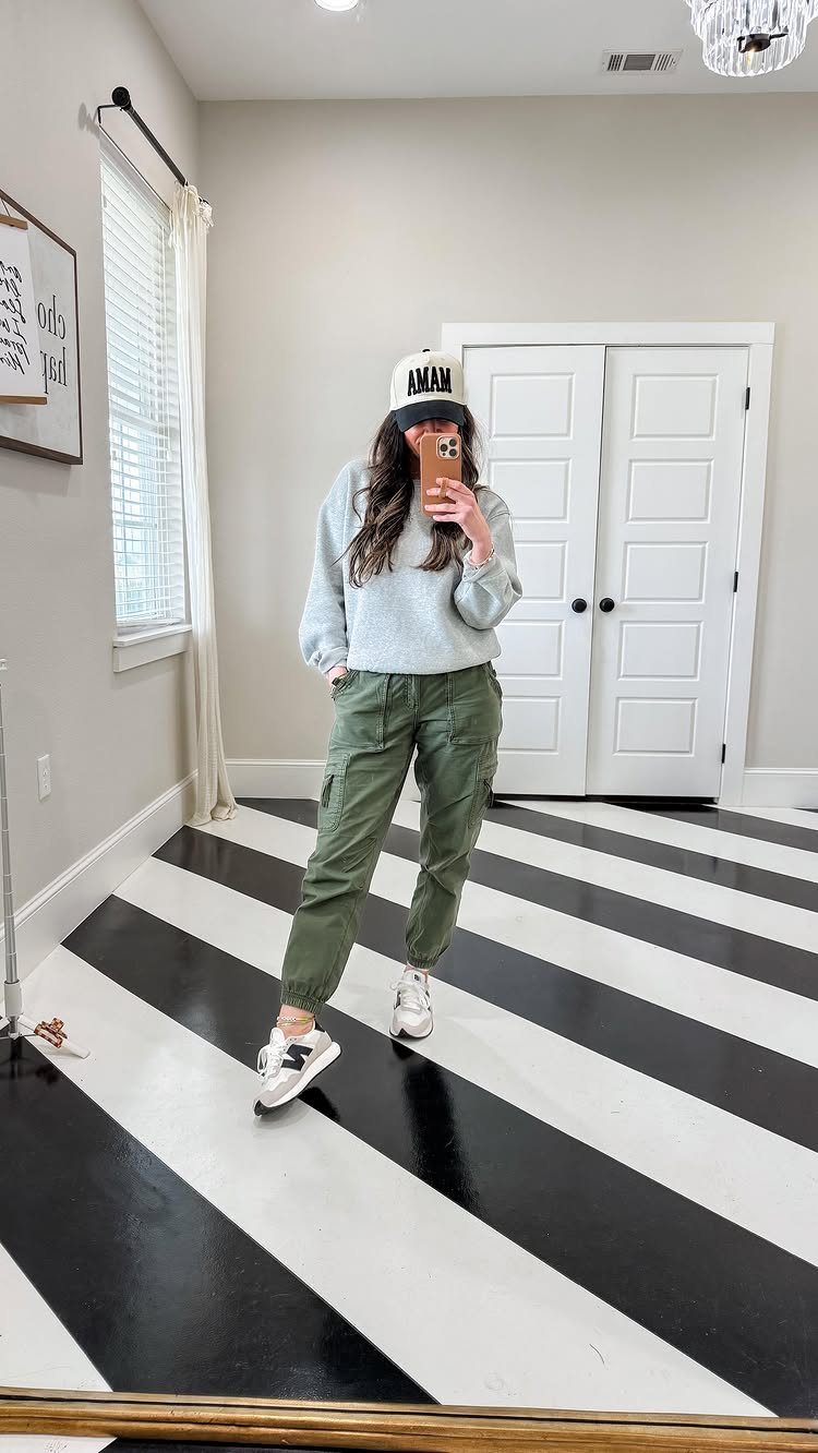 Woman in a gray sweatshirt and olive green cargo joggers posing for a mirror selfie.