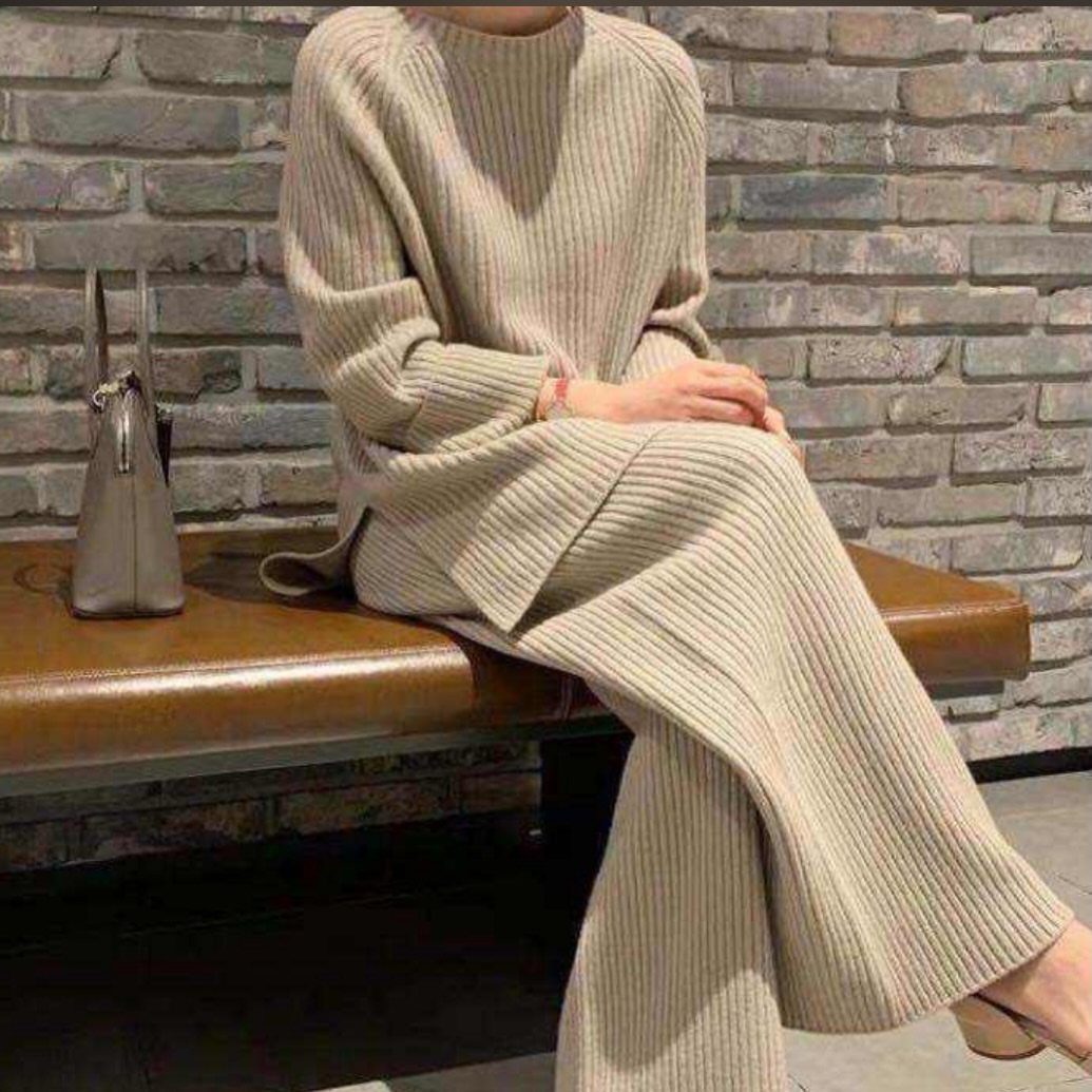 Person wearing a beige ribbed knit sweater and wide-leg lounge pants sitting on a bench.