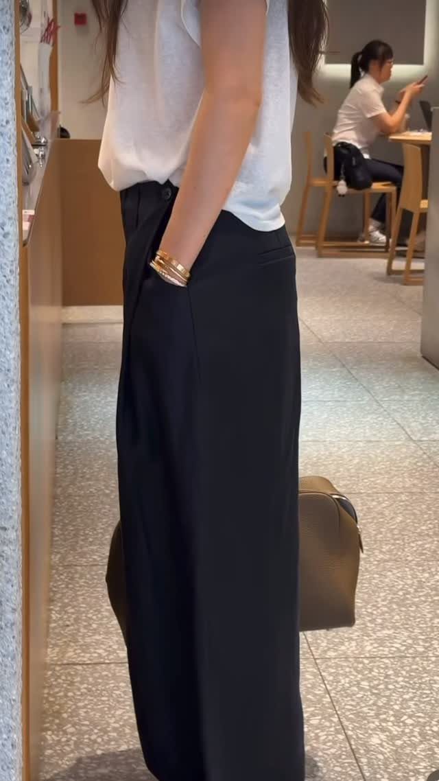 A person wearing a white sleeveless top and black high-waisted tailored trousers.