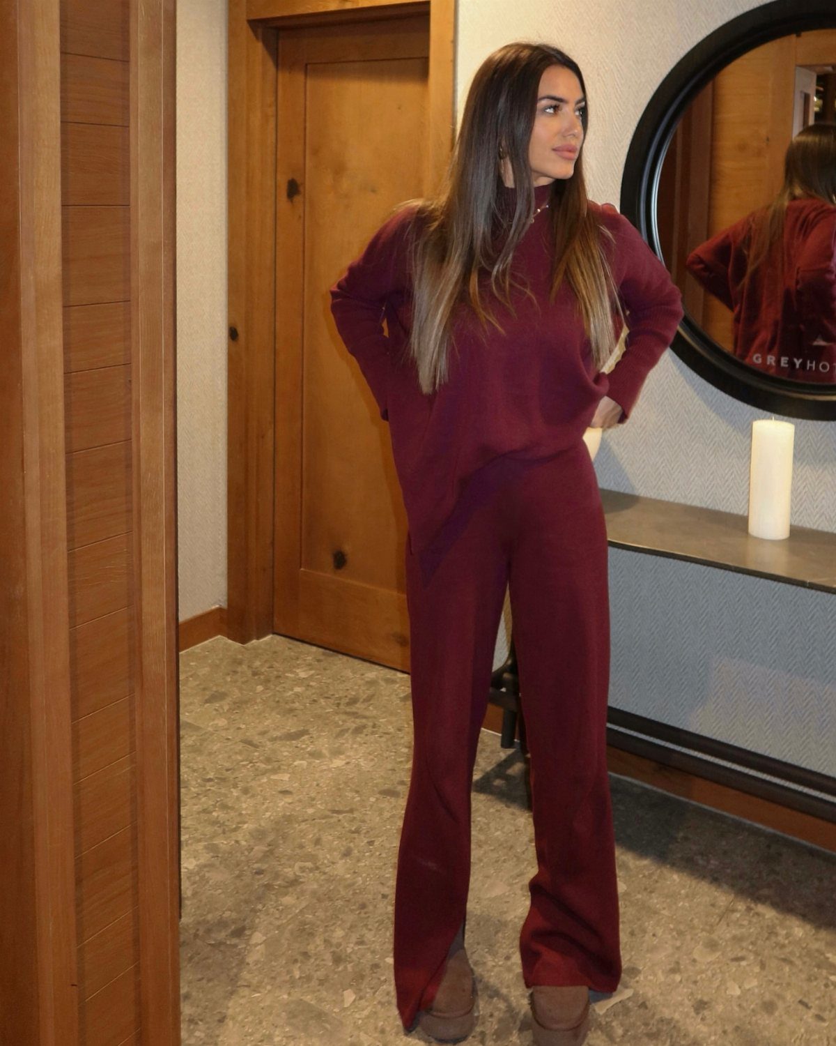A woman posing in a matching maroon long-sleeve top and wide-leg pants set.
