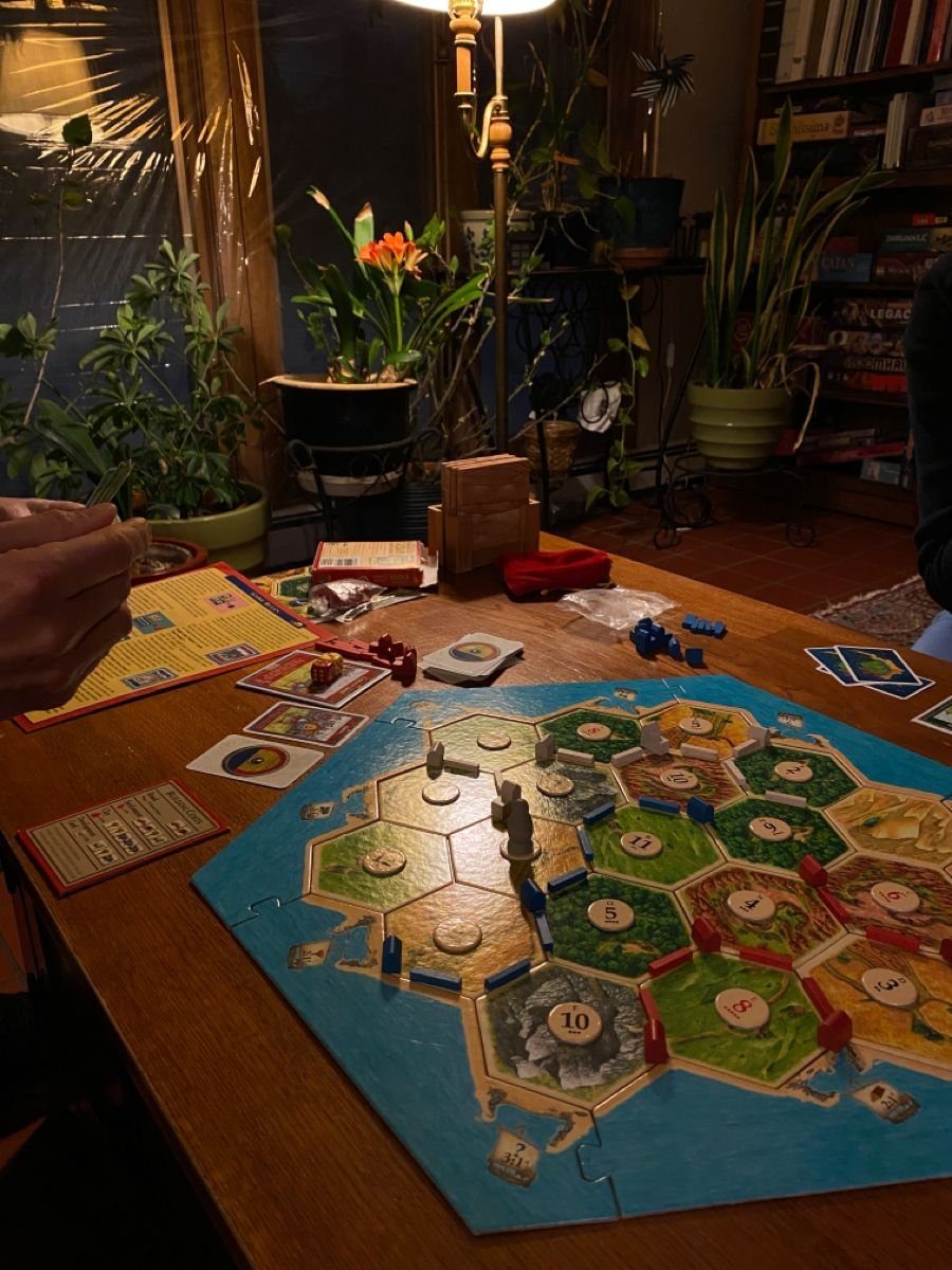 A colorful hexagonal board game spread out on a wooden table in a dimly lit room.