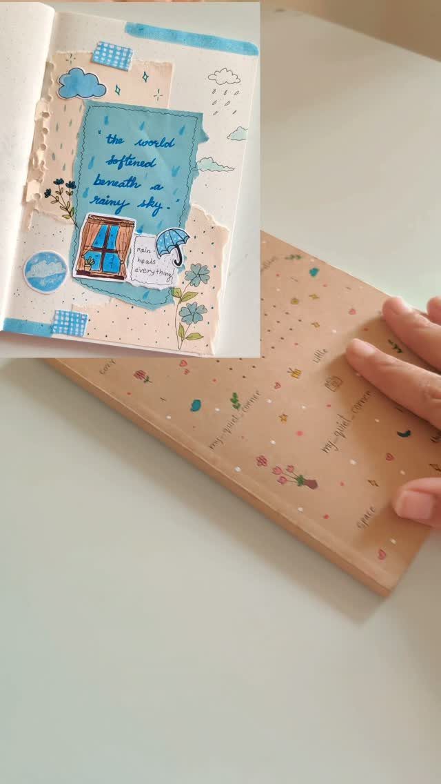 An open decorated journal with stickers and handwriting next to a closed peach notebook.
