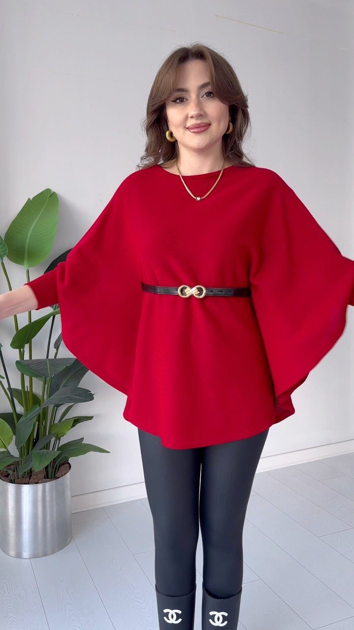 Woman wearing a red belted tunic top with wide sleeves and black leggings.