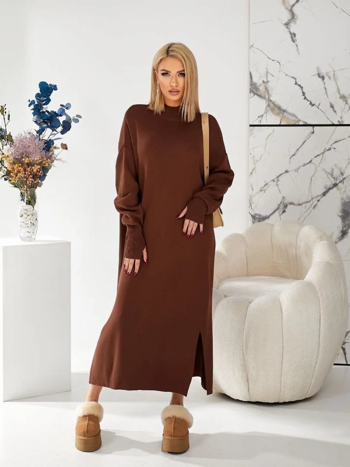 Blonde woman posing in a long brown knit sweater dress with a side slit.