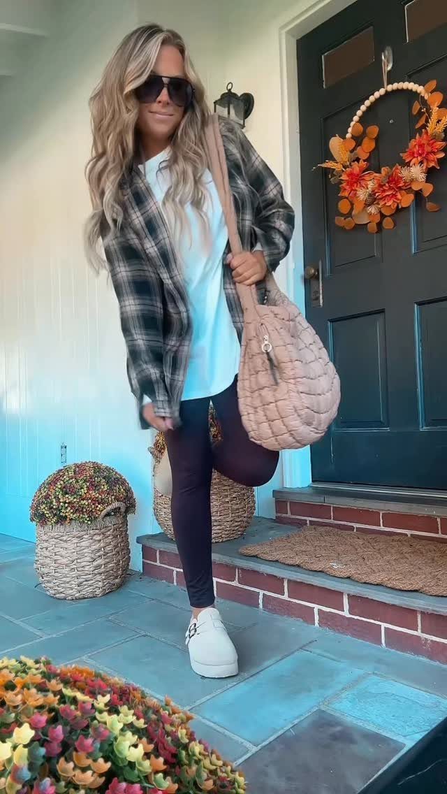 Woman wearing black leggings, a long blue shirt, and a plaid flannel shirt on a porch.