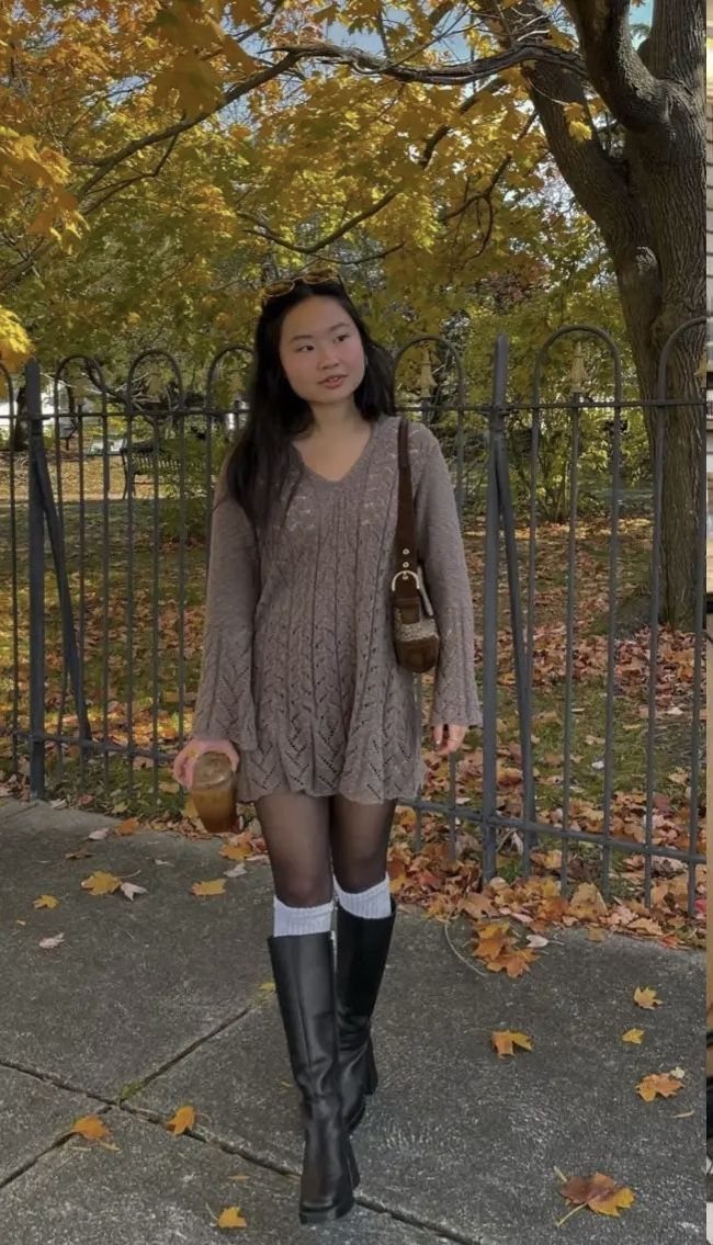 Woman wearing a brown cable-knit sweater dress and tall black boots standing outdoors.