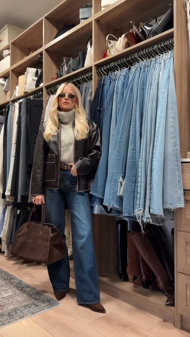 Blonde woman in sunglasses wearing a brown leather jacket and wide-leg jeans standing in a clothing store.