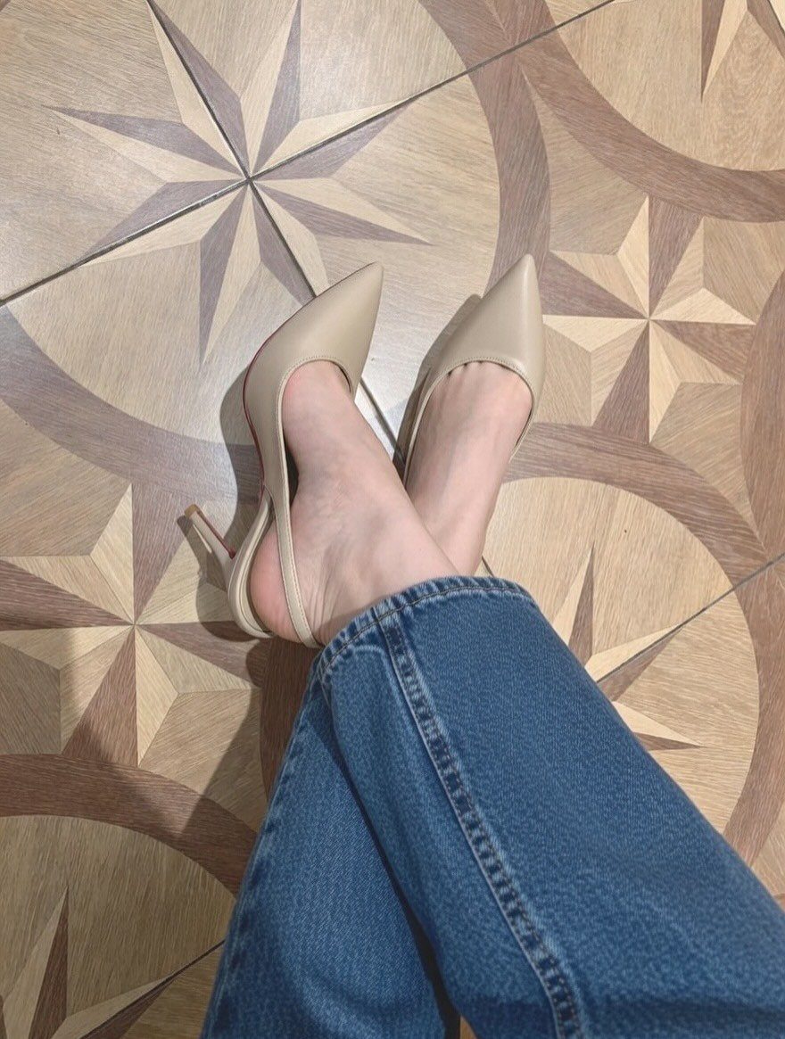 Beige pointed-toe slingback high heels worn with blue denim jeans on patterned tiles.