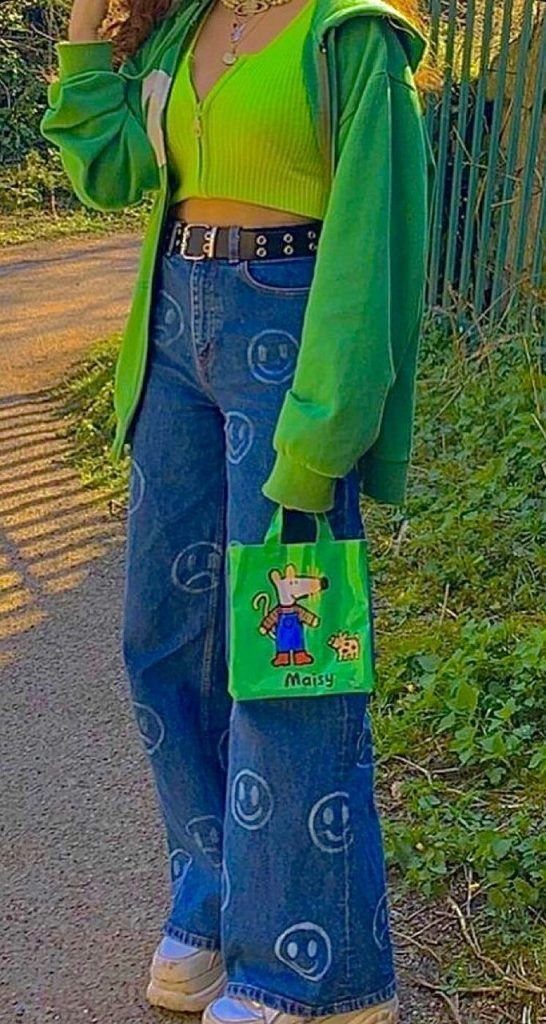 Person wearing baggy blue denim jeans with smiley face patterns and a lime green outfit.
