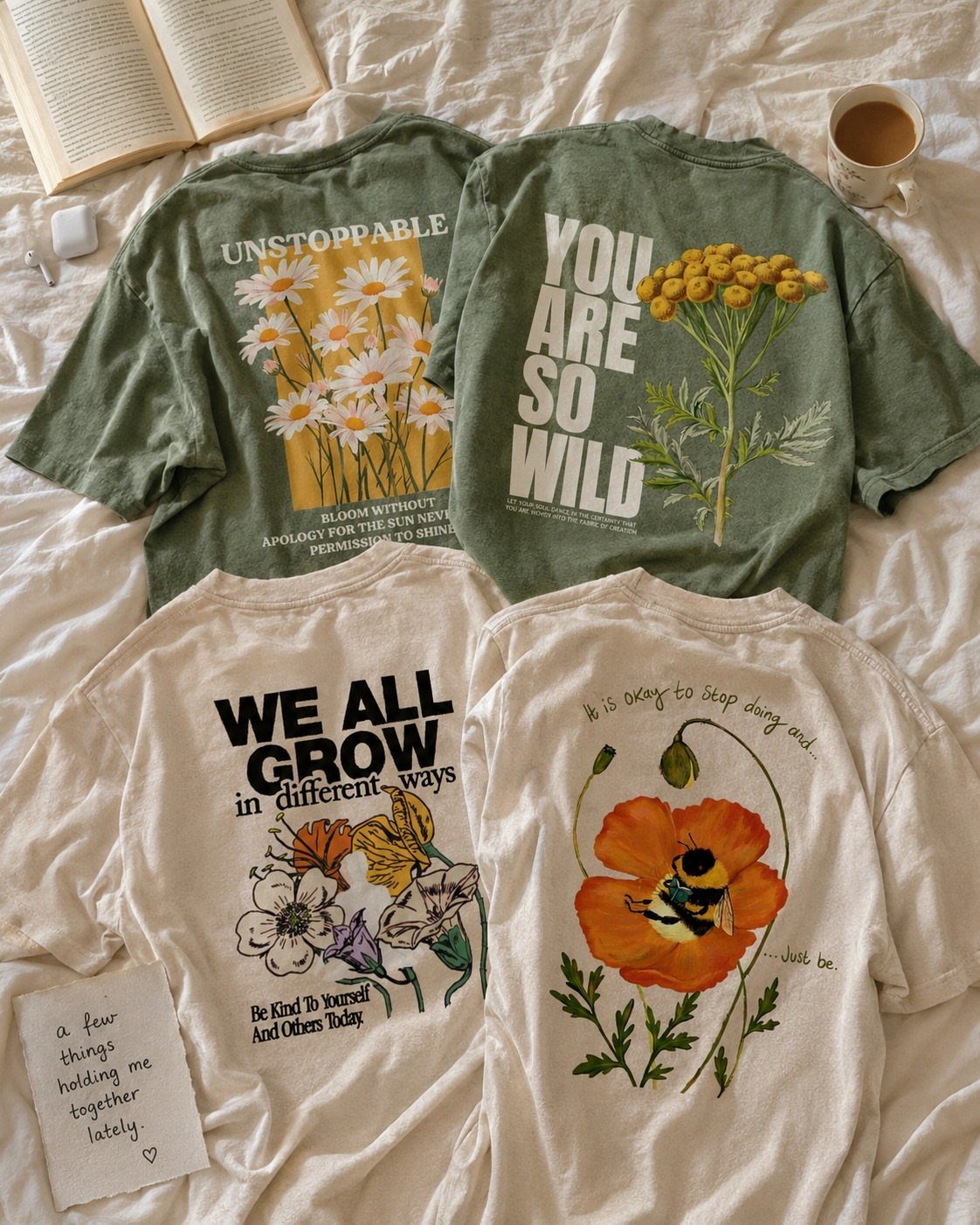 Three graphic t-shirts with floral designs and inspirational text laid on white fabric.