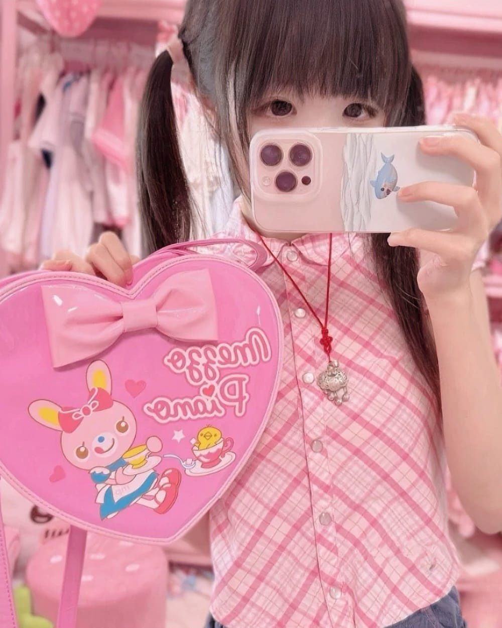 A girl holding a pink heart-shaped kawaii bag with a bunny character and bow.