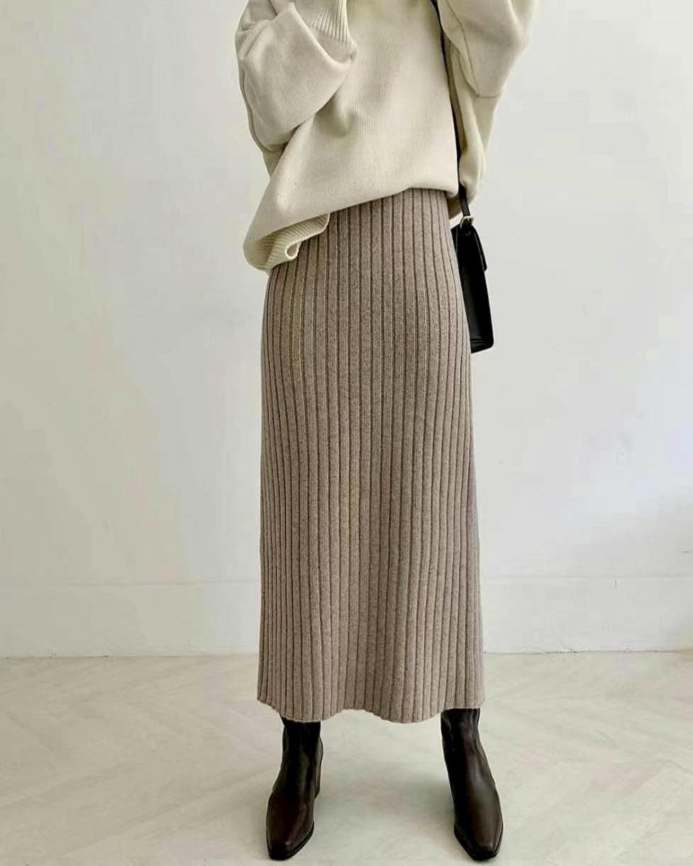 Person wearing a cream sweater and a long ribbed beige skirt with dark boots.