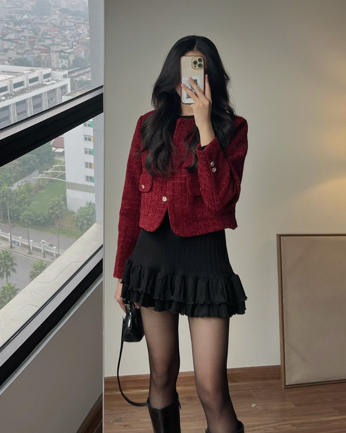 Woman in a red tweed jacket and black ruffled skirt taking a mirror selfie.