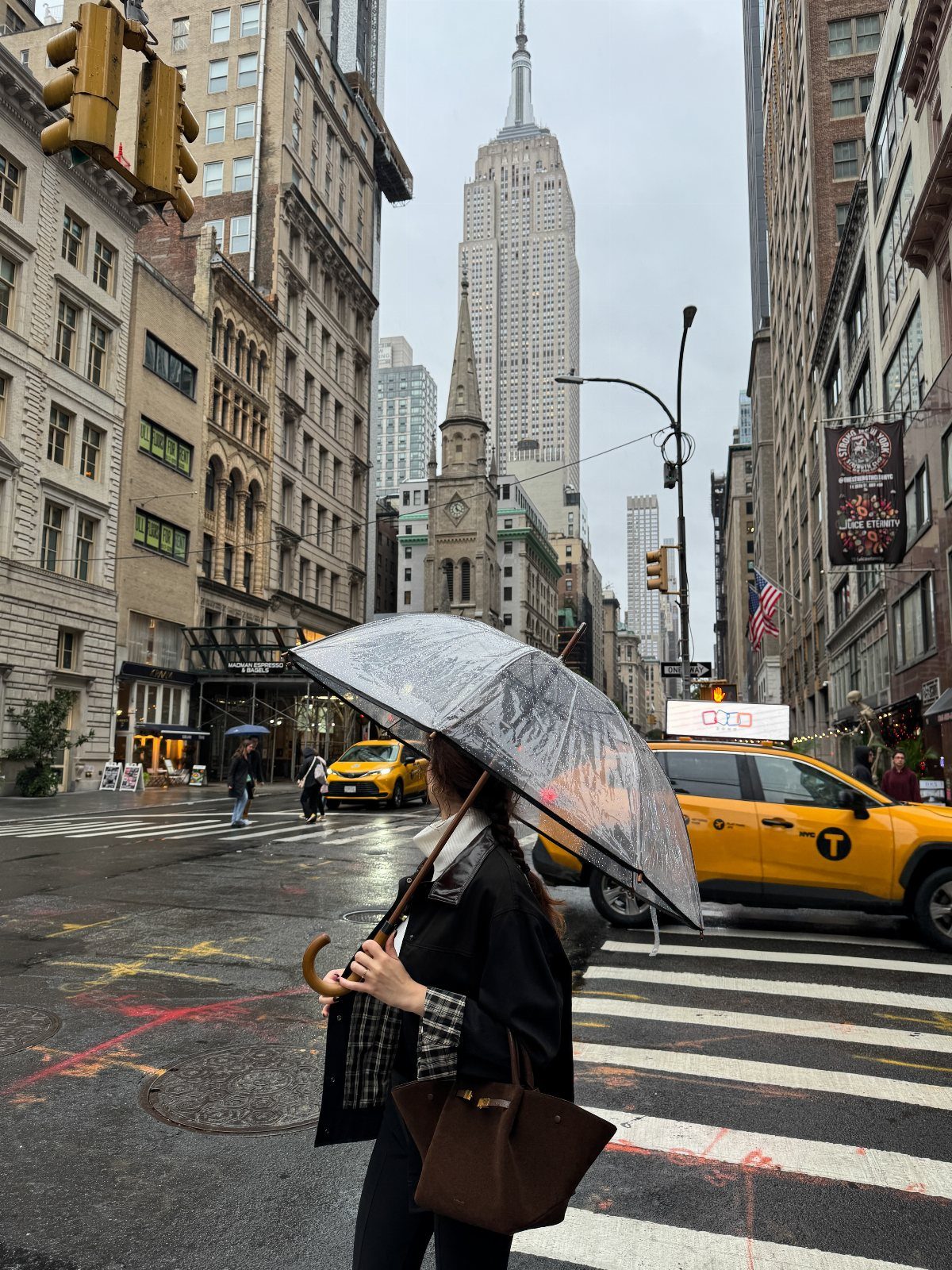 A person walking through a rainy New York City street holding a clear umbrella.