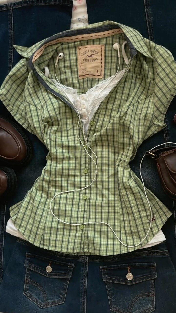 Green plaid shirt layered over a white lace camisole on blue denim jeans.