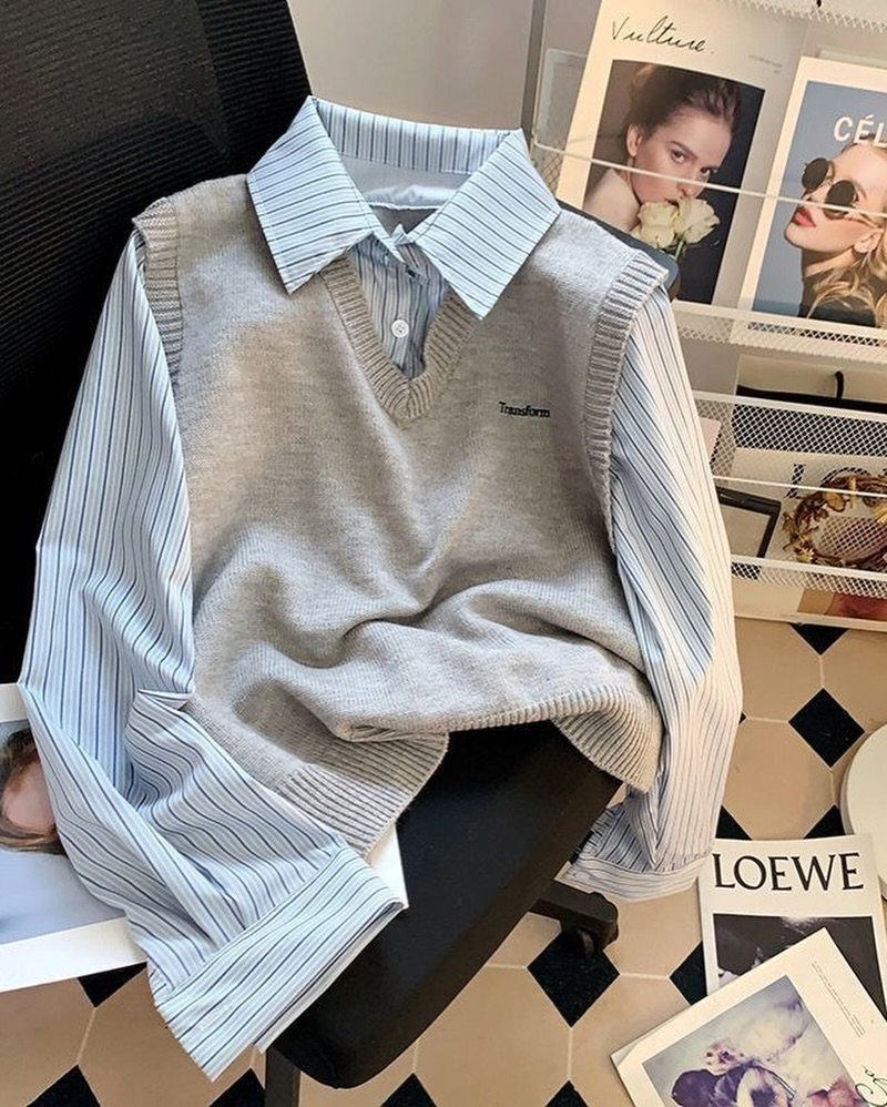 A grey V-neck sweater vest layered over a blue striped collared shirt on a chair.