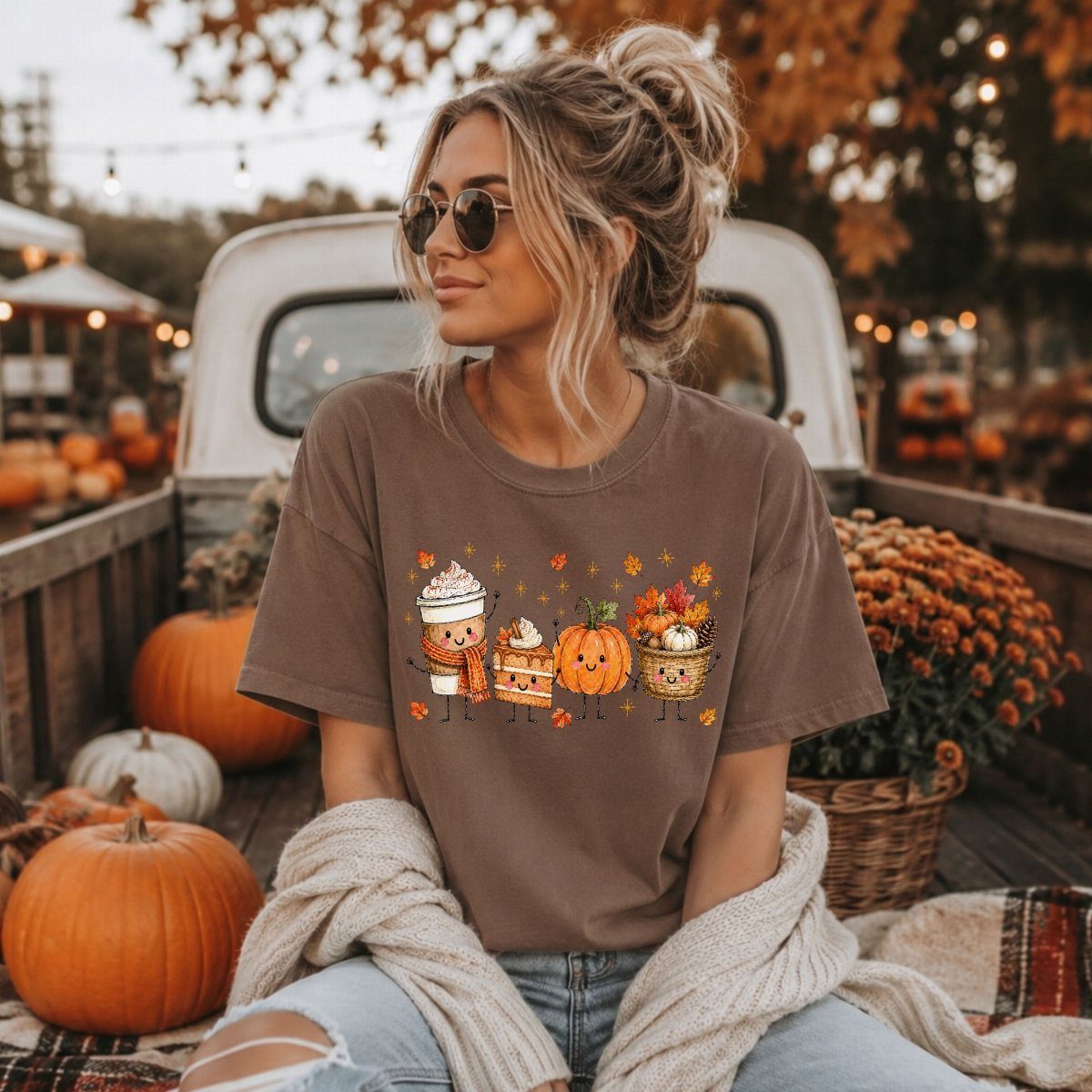 Woman in a brown graphic t-shirt sitting among pumpkins in a vintage truck bed.
