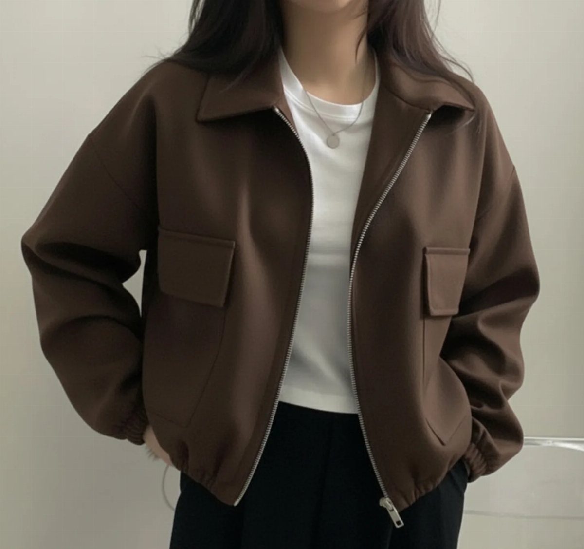 A person wearing a brown zip-up bomber jacket with large chest pockets over a white shirt.