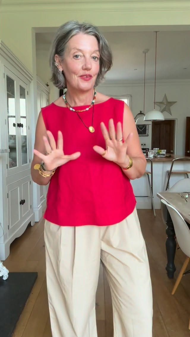 A woman wearing a pink sleeveless top and beige wide-leg comfortable pants in a kitchen.