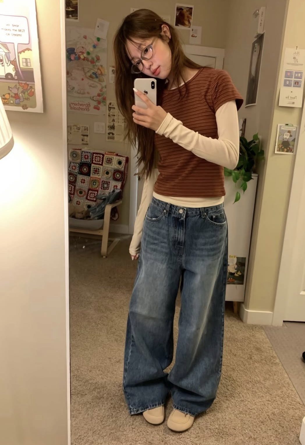 Woman in a brown t-shirt layered over a cream long-sleeve top and wide-leg jeans.
