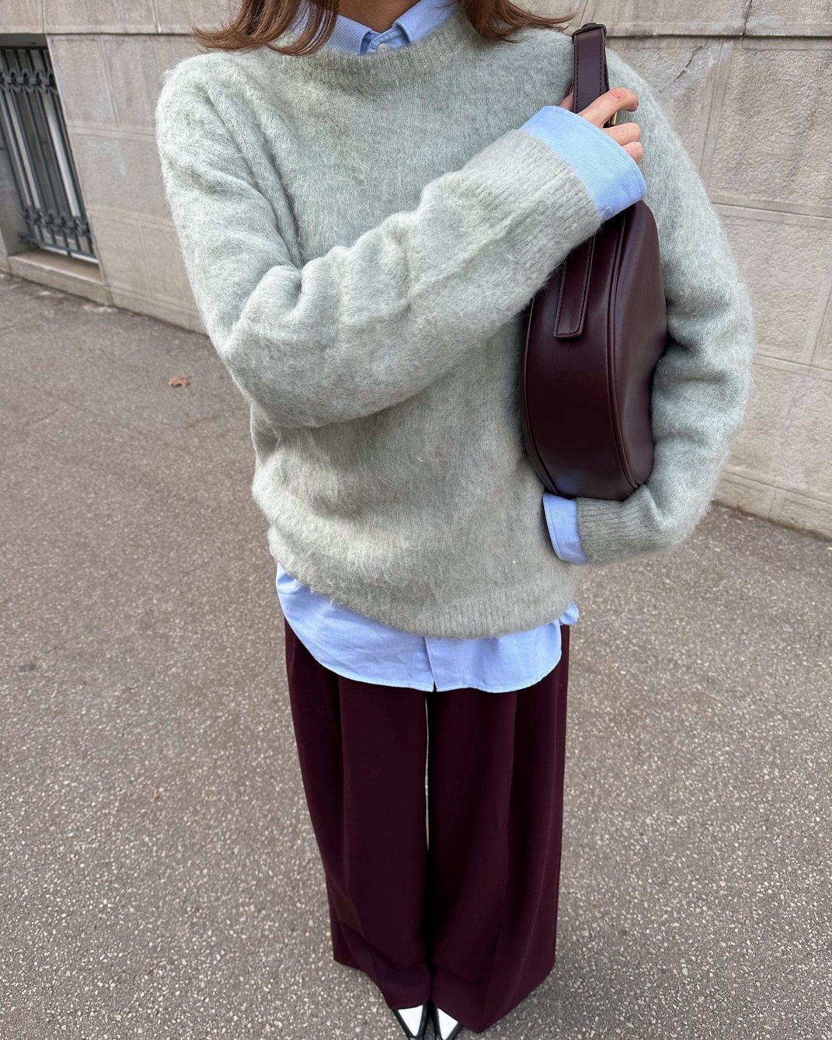 Person wearing a sage green oversized sweater, blue collared shirt, and burgundy tailored trousers.
