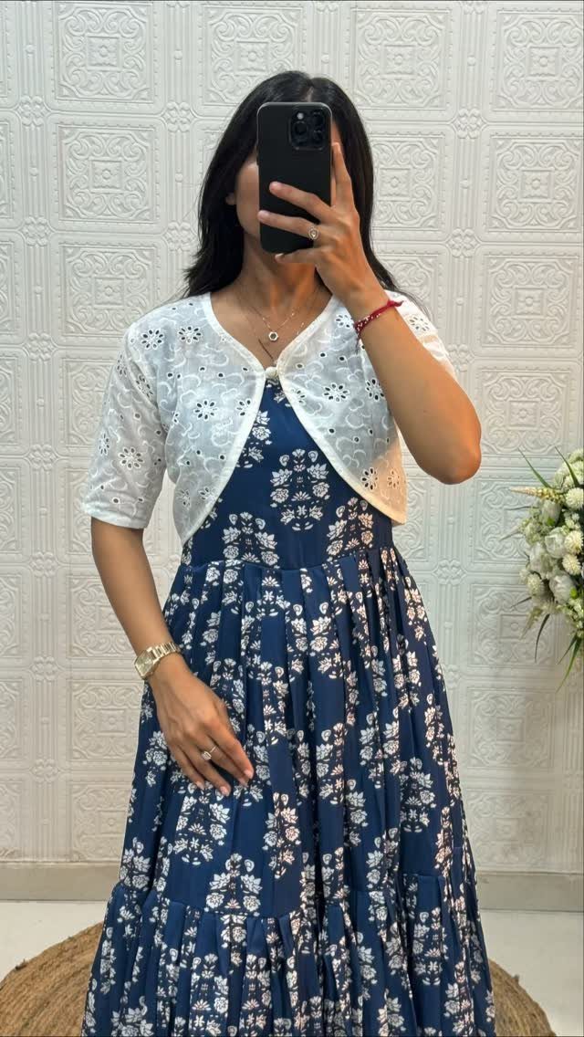 Woman in a navy blue floral maxi dress and white lace cardigan taking a selfie.
