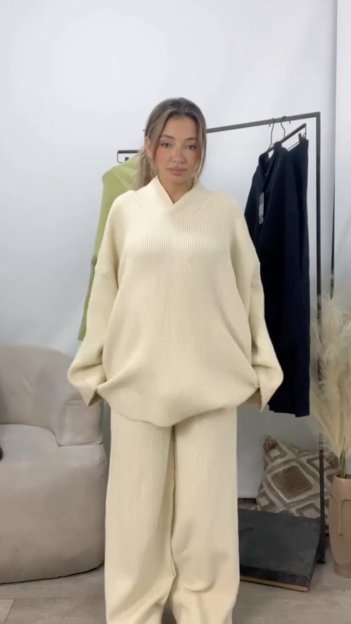A woman posing in a cream ribbed knit matching sweater and wide-leg pants set.