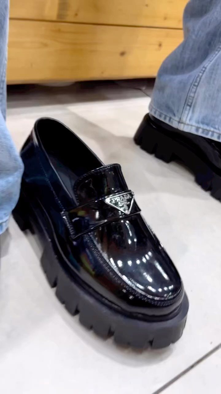 Black patent leather chunky loafers with a thick lug sole and silver logo detail.