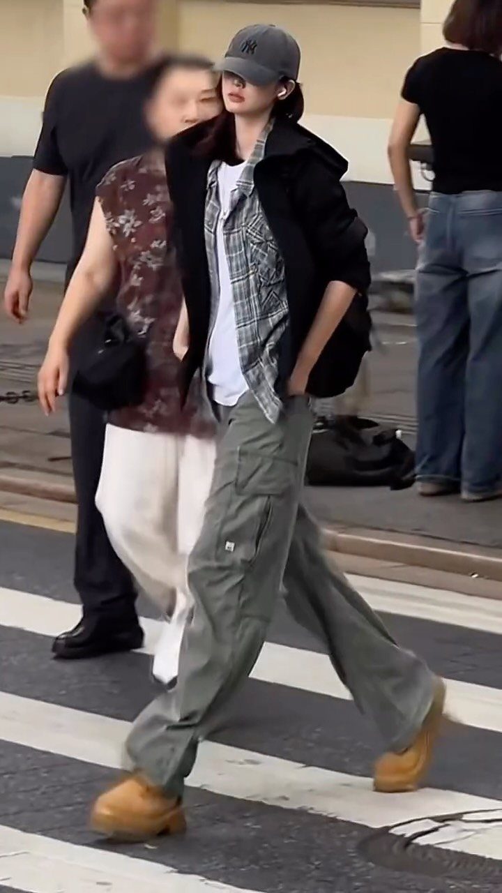 A person walking in a street wearing olive green wide-leg cargo pants and tan boots.