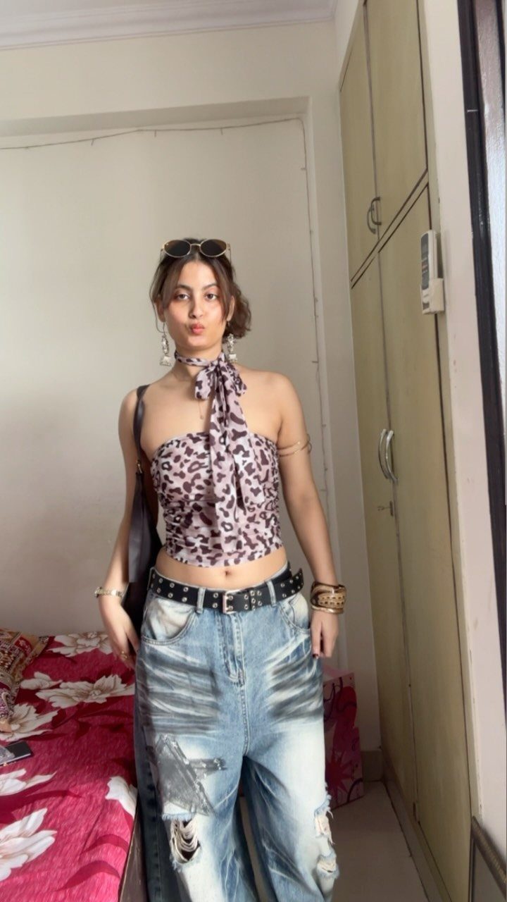 Woman wearing a leopard print halter top and baggy distressed denim jeans.