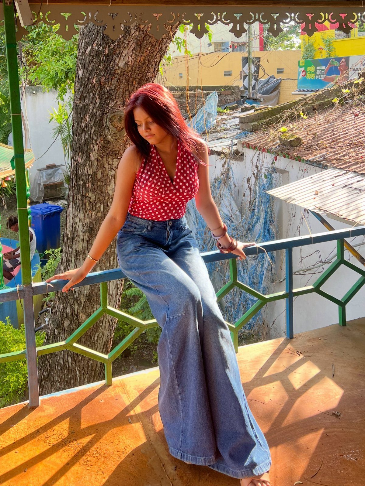 A woman wearing a red polka dot halter top and wide-leg blue denim jeans.