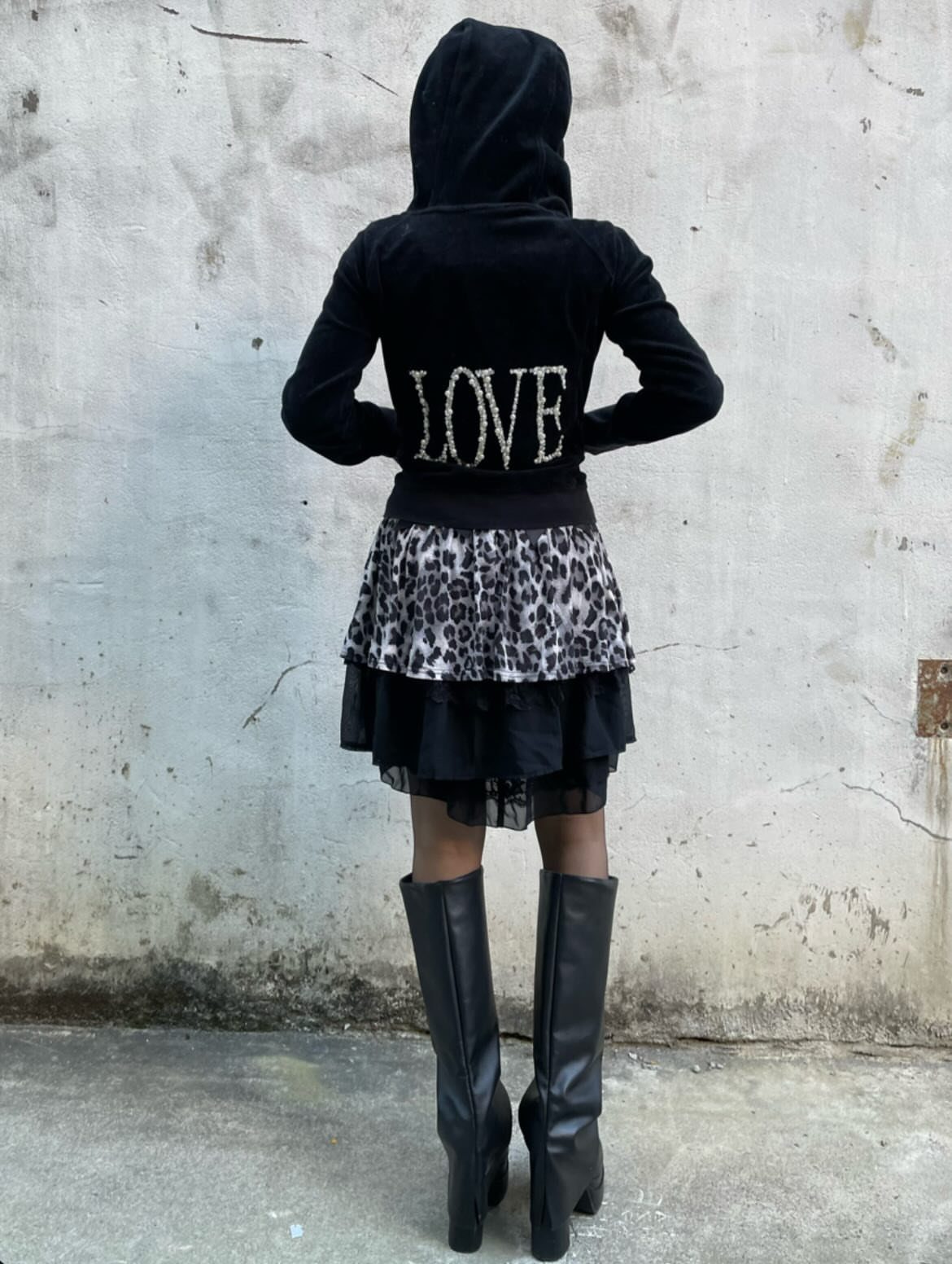 Person wearing a black velvet hoodie with LOVE text, leopard skirt, and black boots.